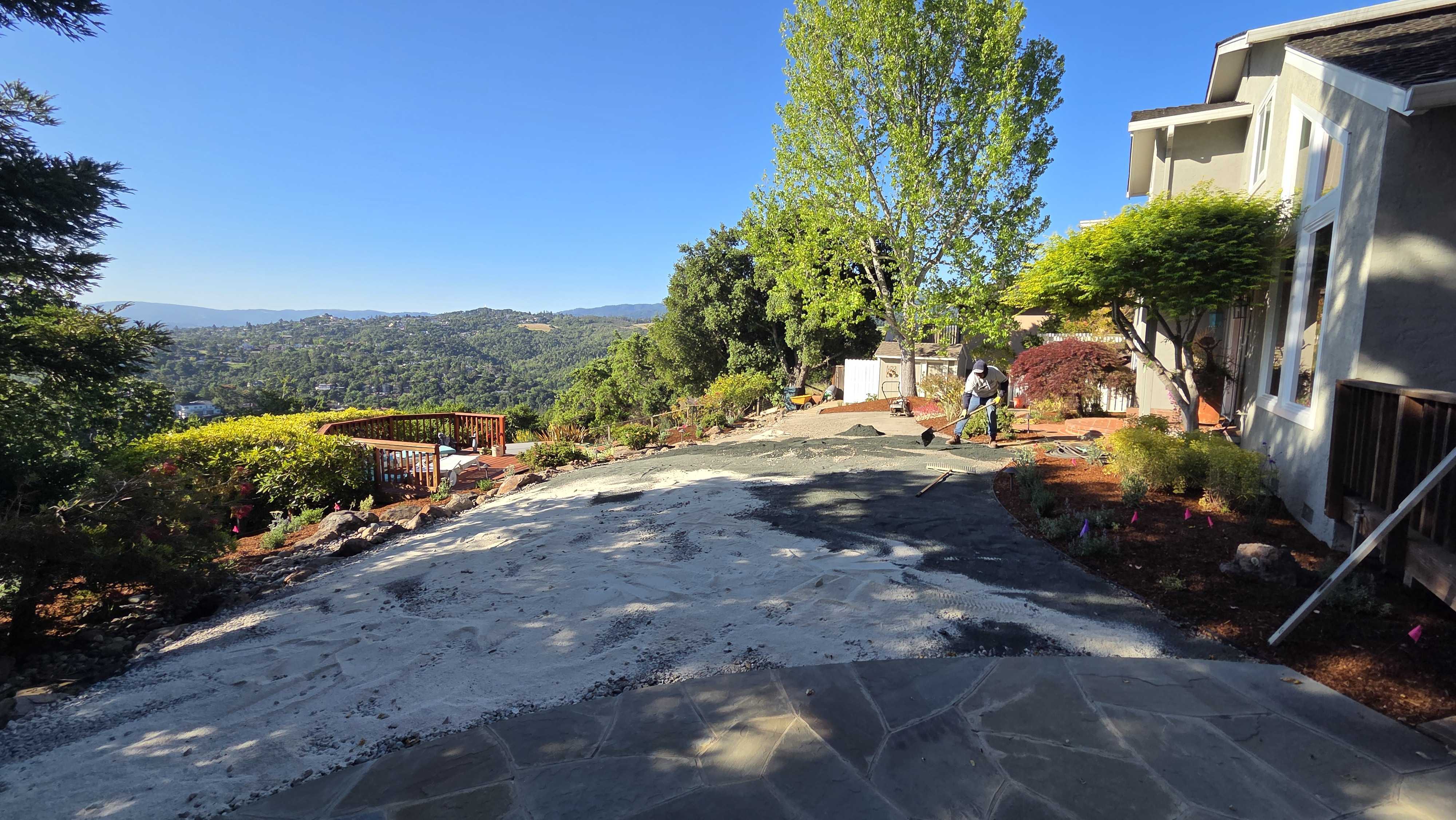 Hillside residential patio/driveway area adjacent to the house showing irregular flagstone pavers partially installed...