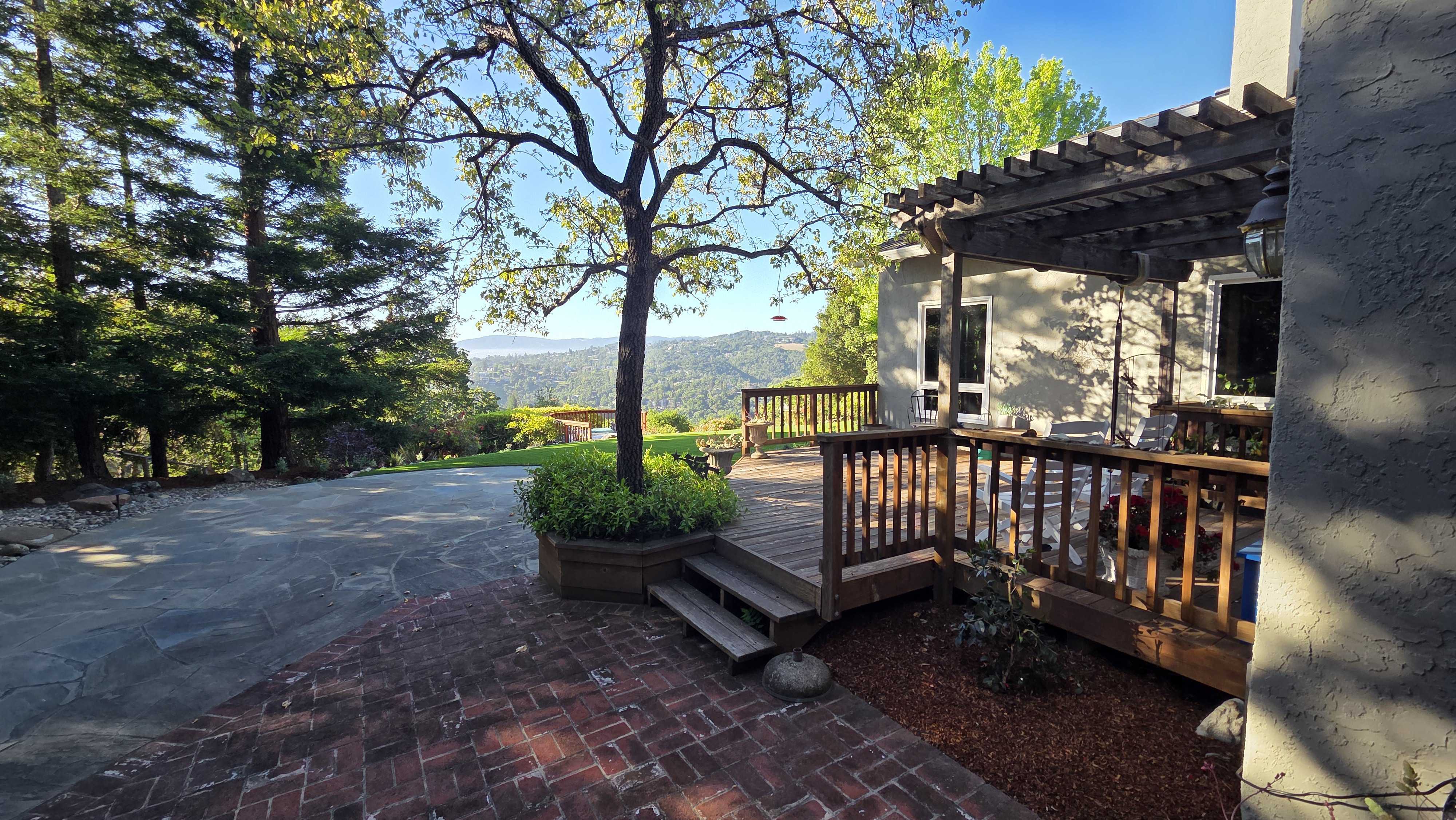 Finished residential backyard showing an interlocking red paver patio transitioning to a large flagstone area with a...