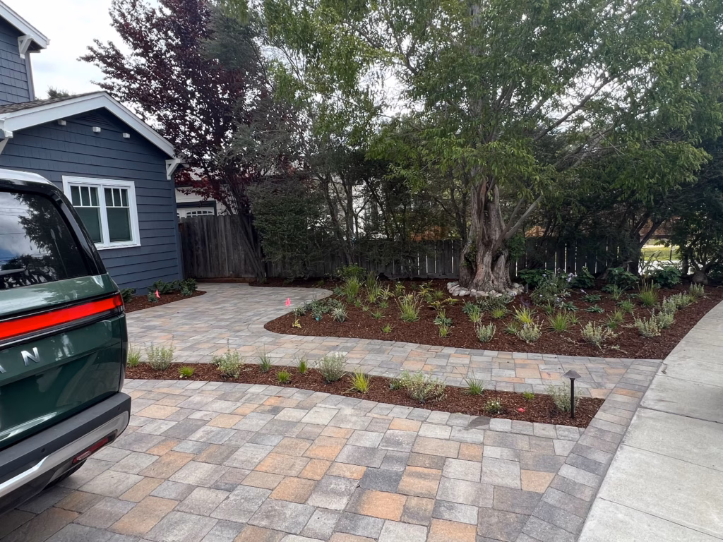 Front yard shows a completed interlocking paver driveway and matching walkway leading to the home, with neatly edged...