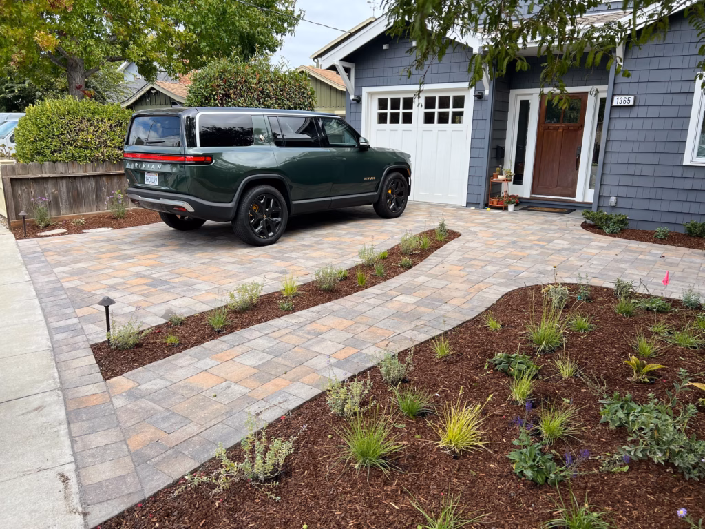 Finished interlocking paver driveway and coordinating walkway leading to the front entry of a single-family home,...