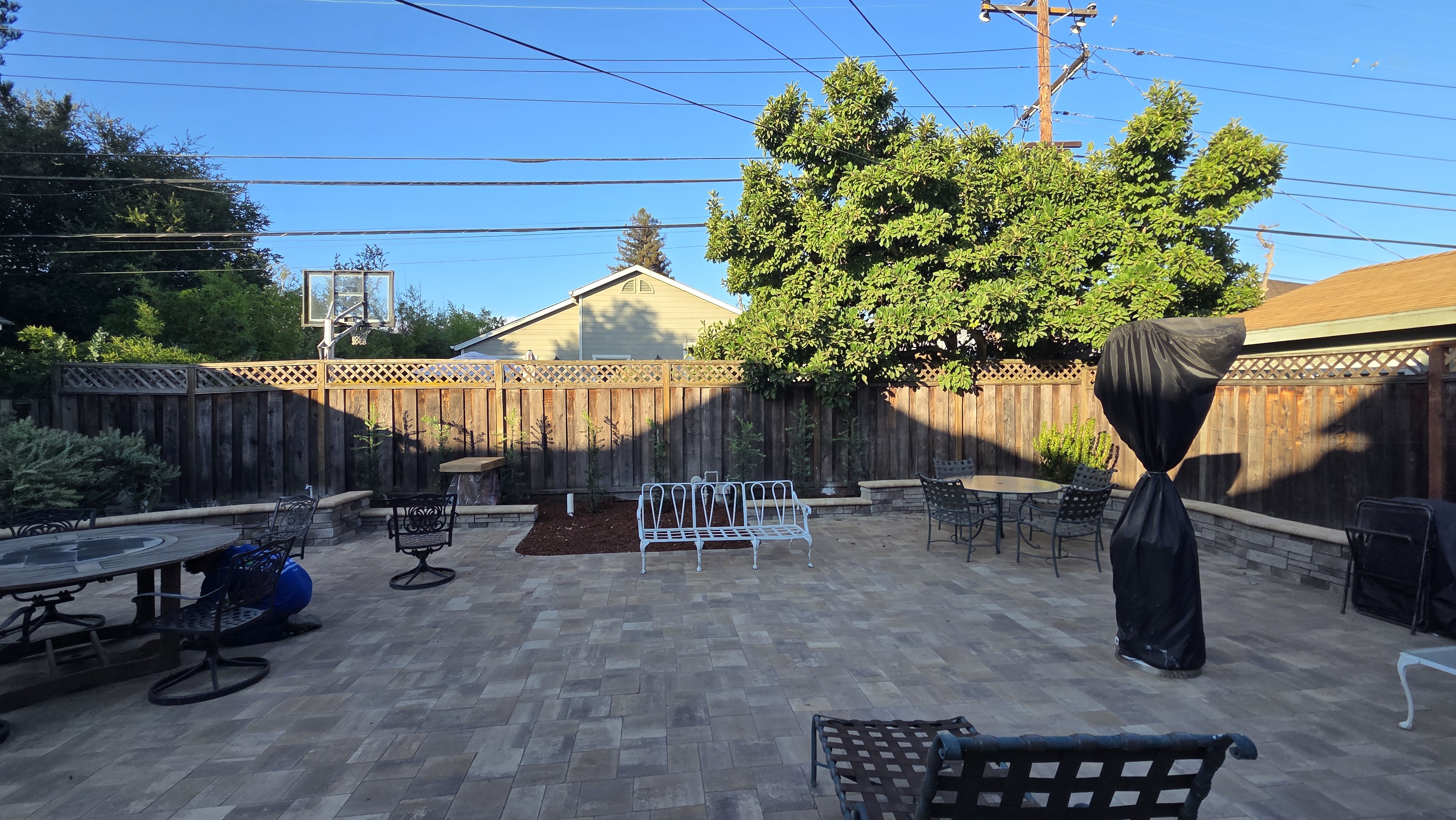 Finished Techo-Bloc paver patio with a low segmental seat wall curving along the planting beds and fence.