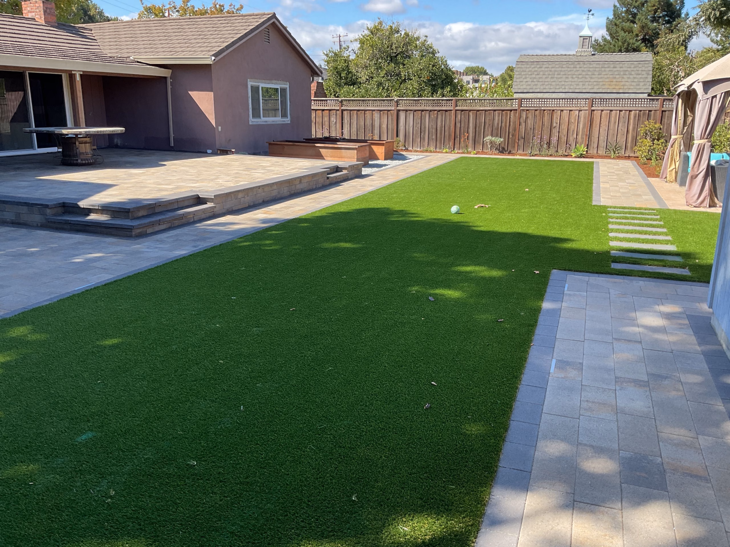 Best hero: broad finished turf, pavers, raised edges, and house context.