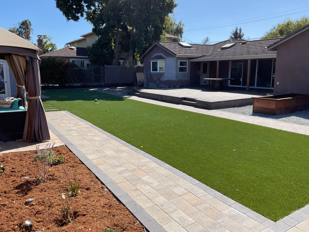 Finished turf and paver border from the rear-yard angle.