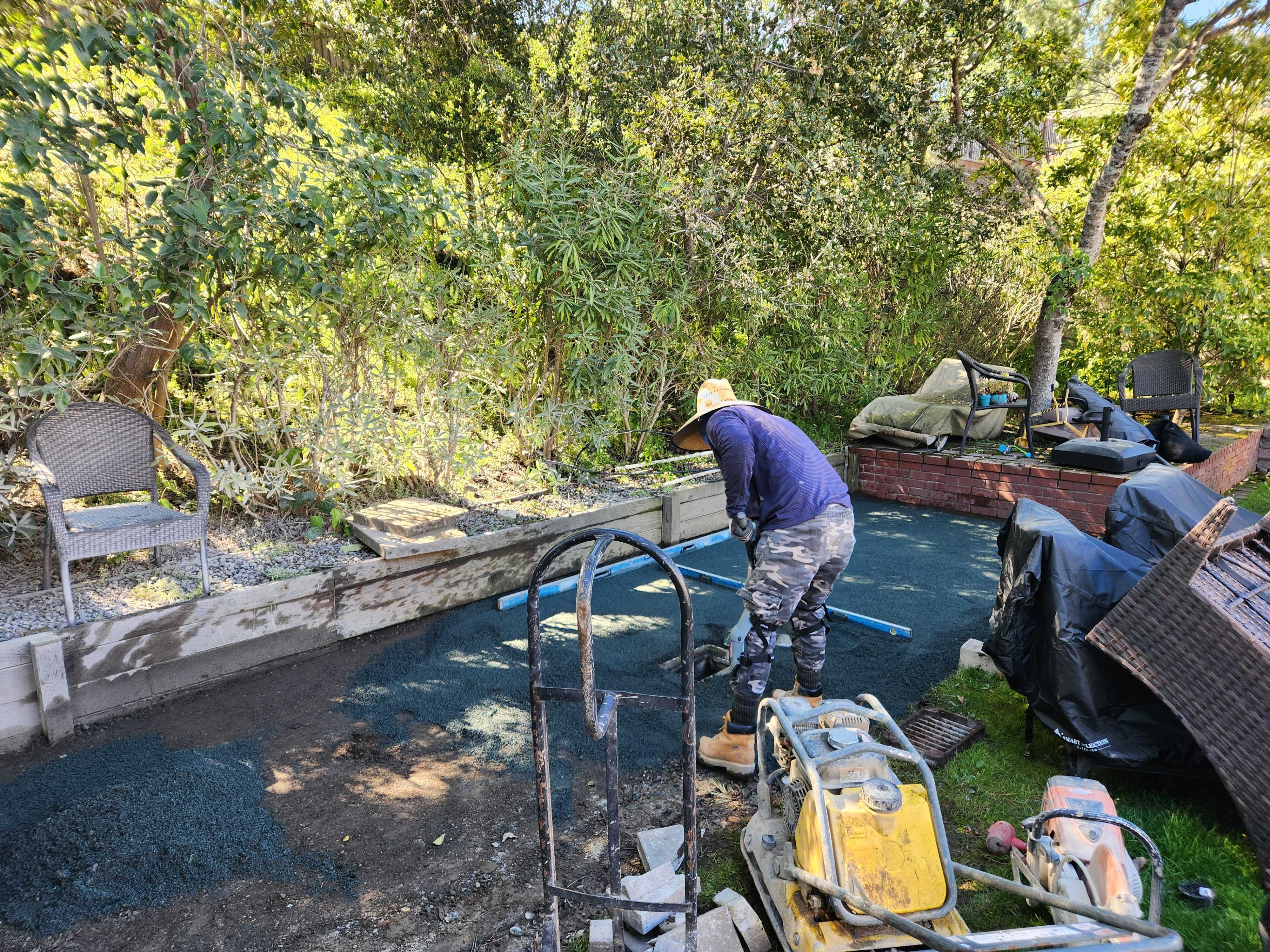 Crew compacting the aggregate base during backyard patio preparation
