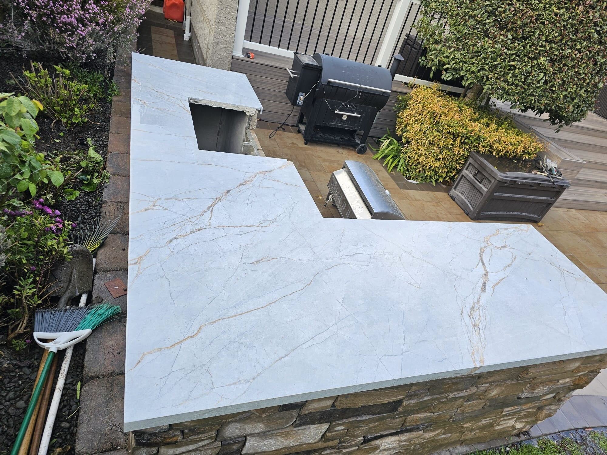 Honed light-stone countertop slab being set on the stacked-stone outdoor-kitchen island