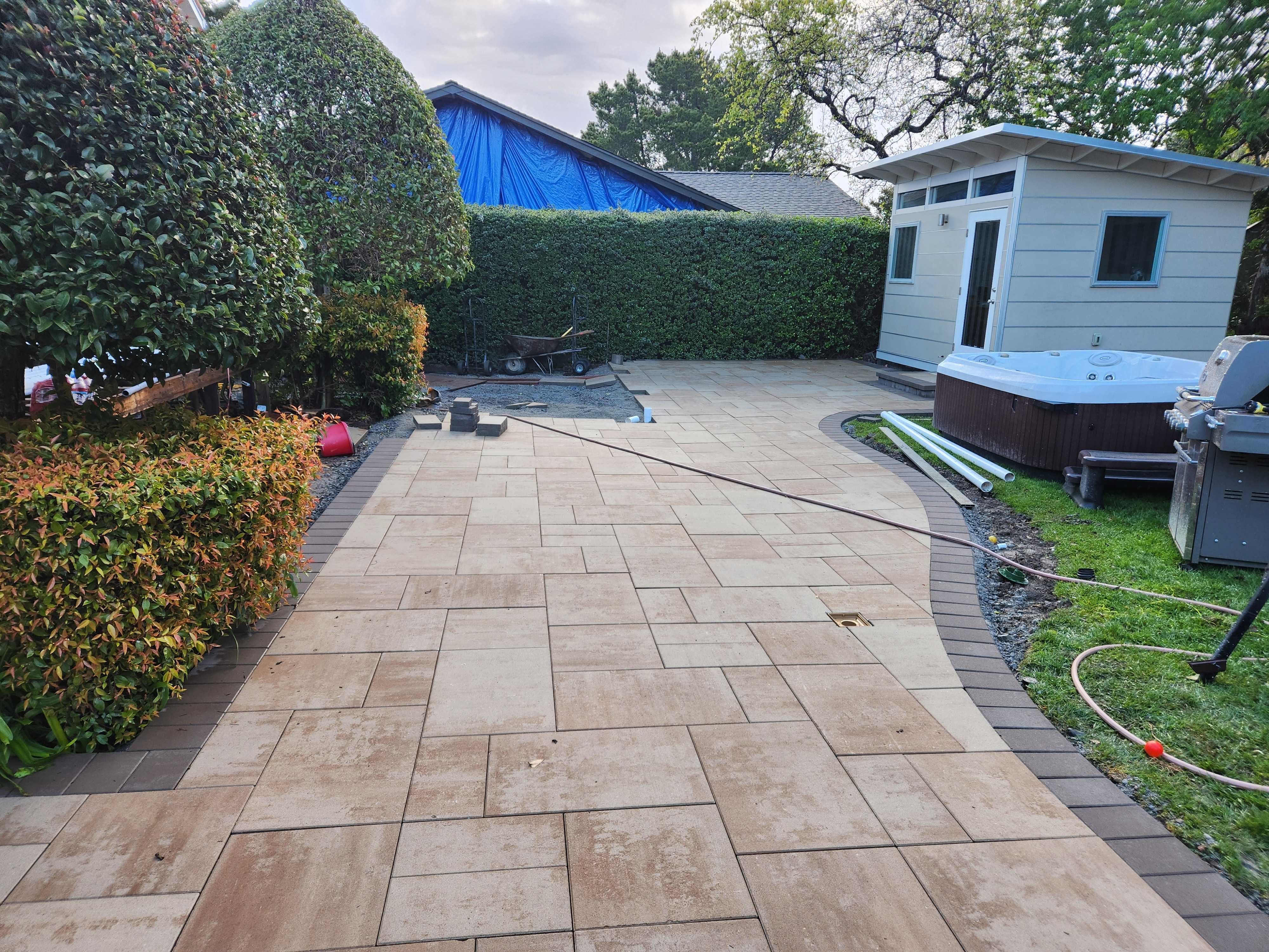 Interlocking paver field with a curved soldier-course border across the new patio.