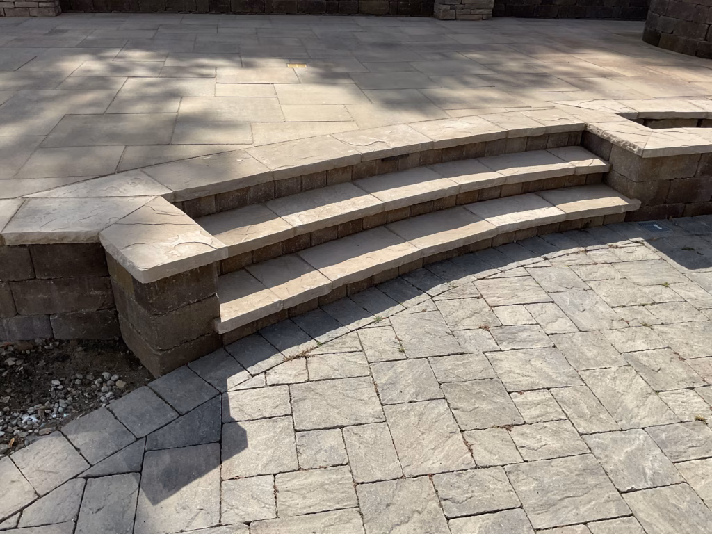 Curved three-step bullnose stone treads connecting a lower paver area to the upper patio