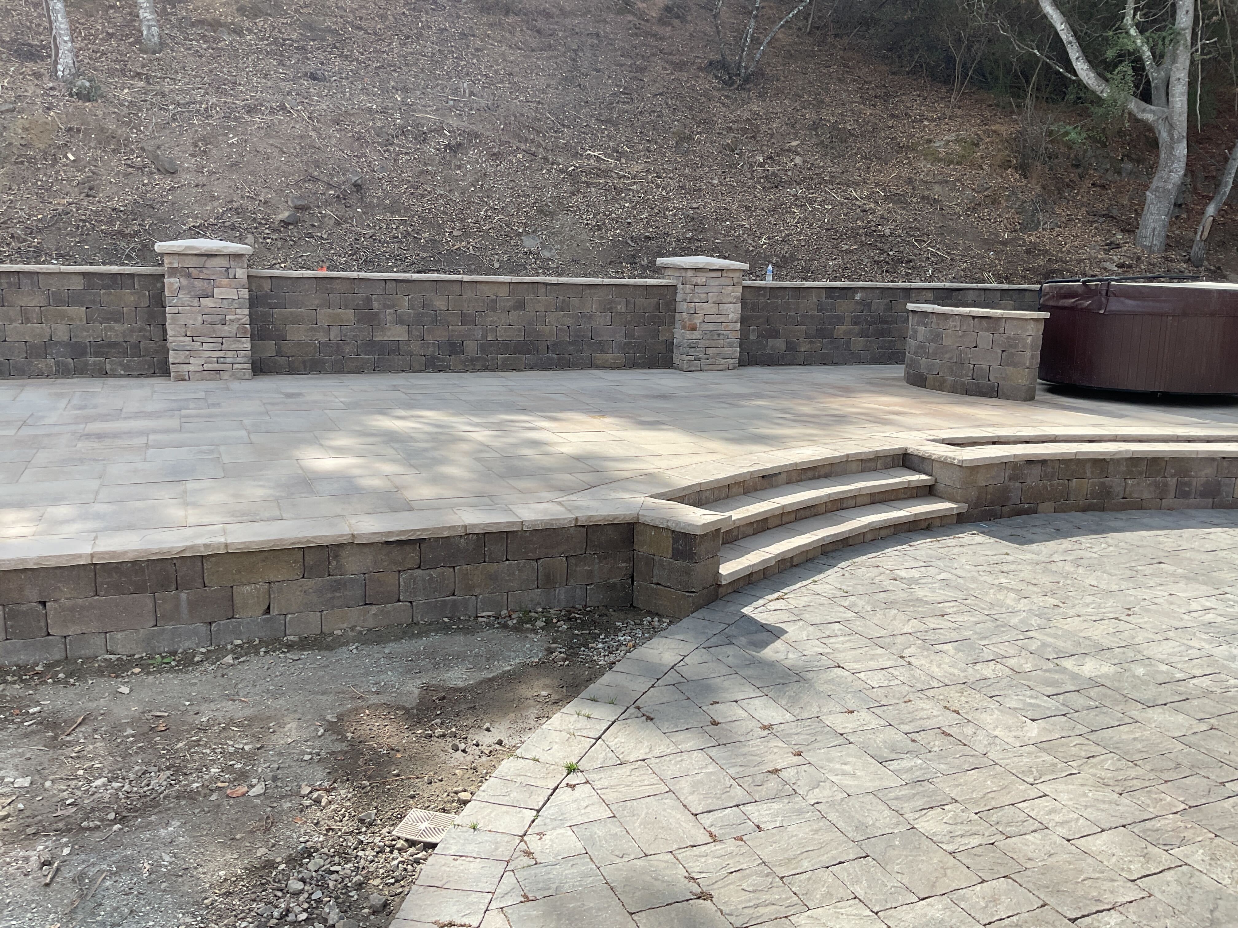 Multi-level paver patio with curved bullnose stone steps and segmental retaining wall