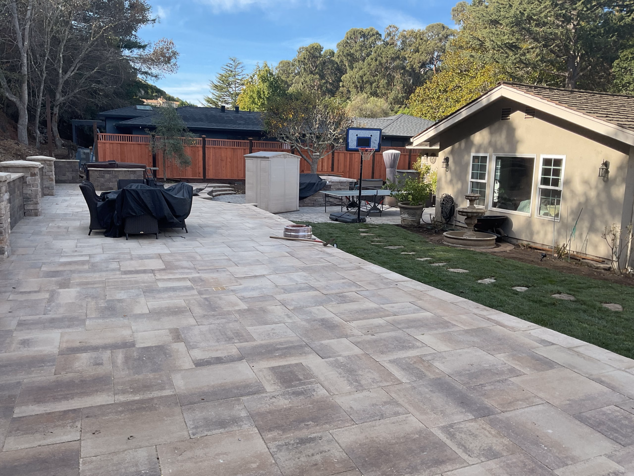 Wide backyard view with finished paver patio, fenced yard, and seating area against the rear of the home