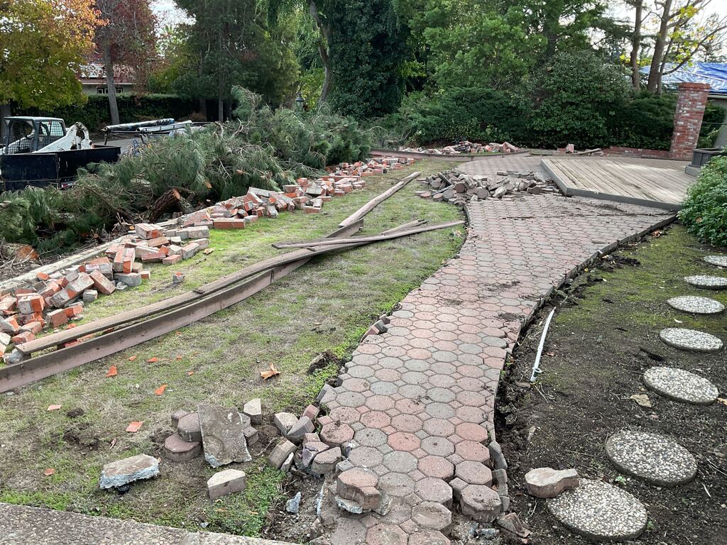 Old hexagonal paver walkway and brick edging being removed from the back yard during demolition.