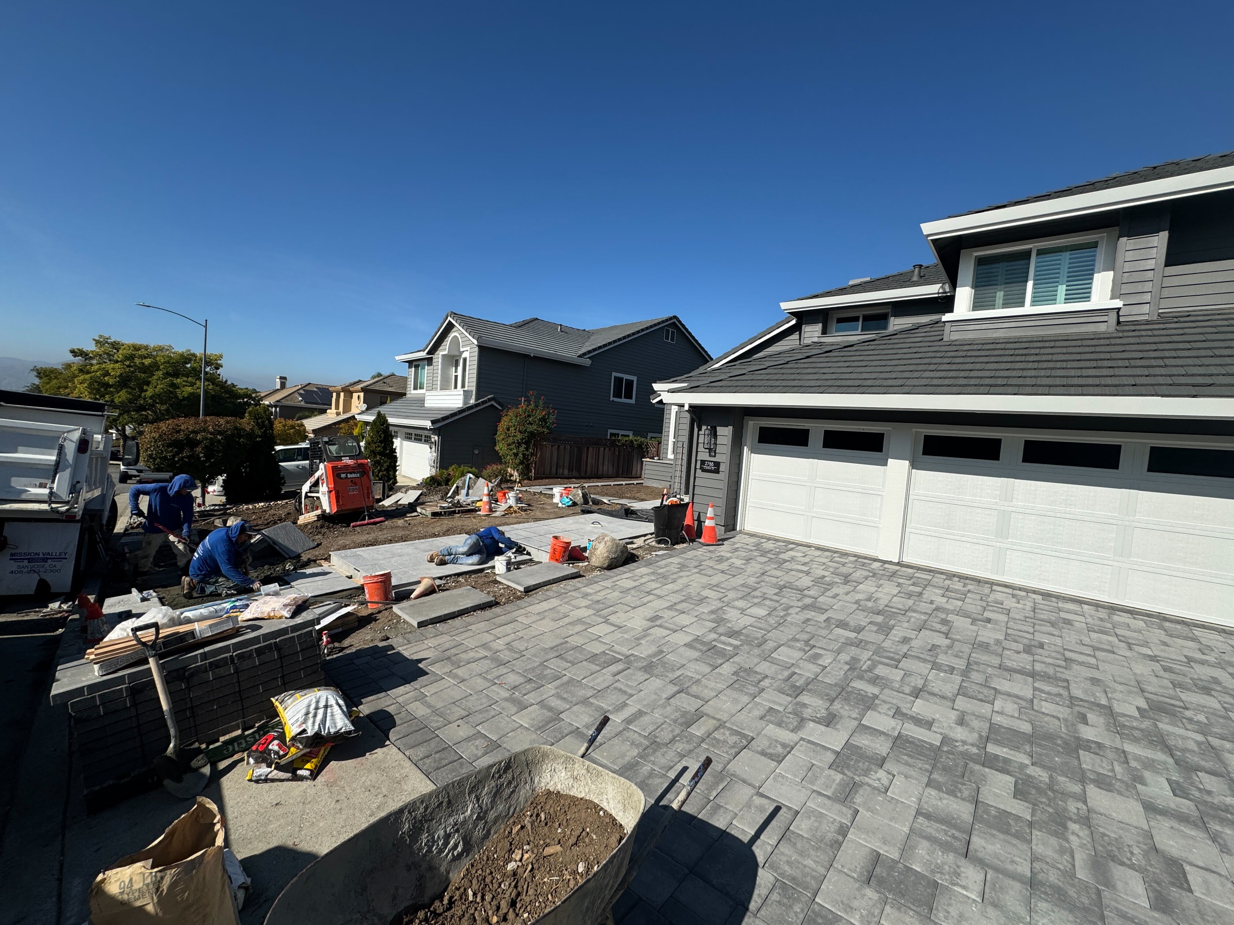 Crew setting the gray paver driveway field with the entry walkway pavers taking shape alongside.