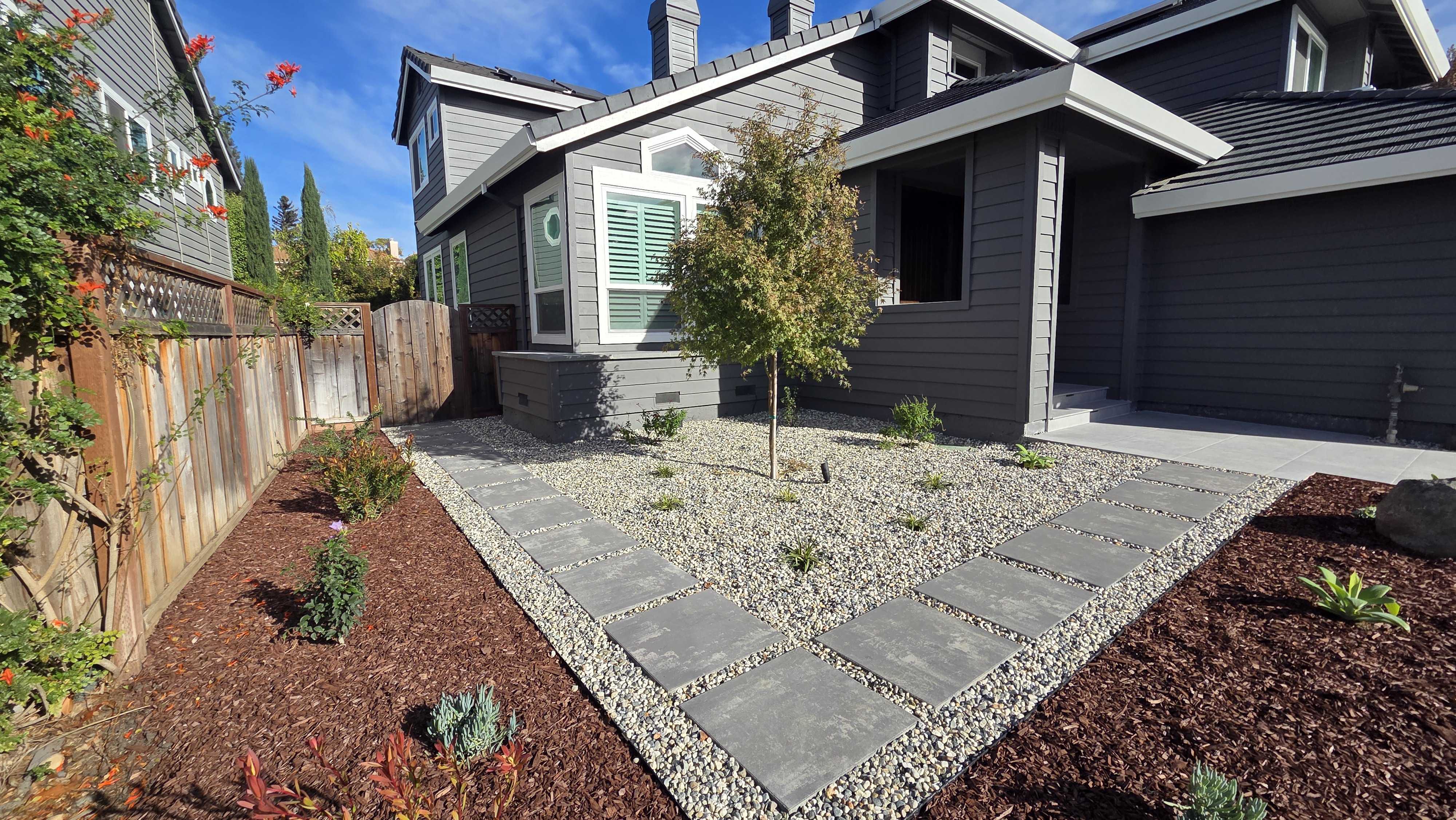 Red-bark mulch planting field with granite boulders, drought-tolerant succulents, and ornamental grasses across the Morgan Hill front yard.
