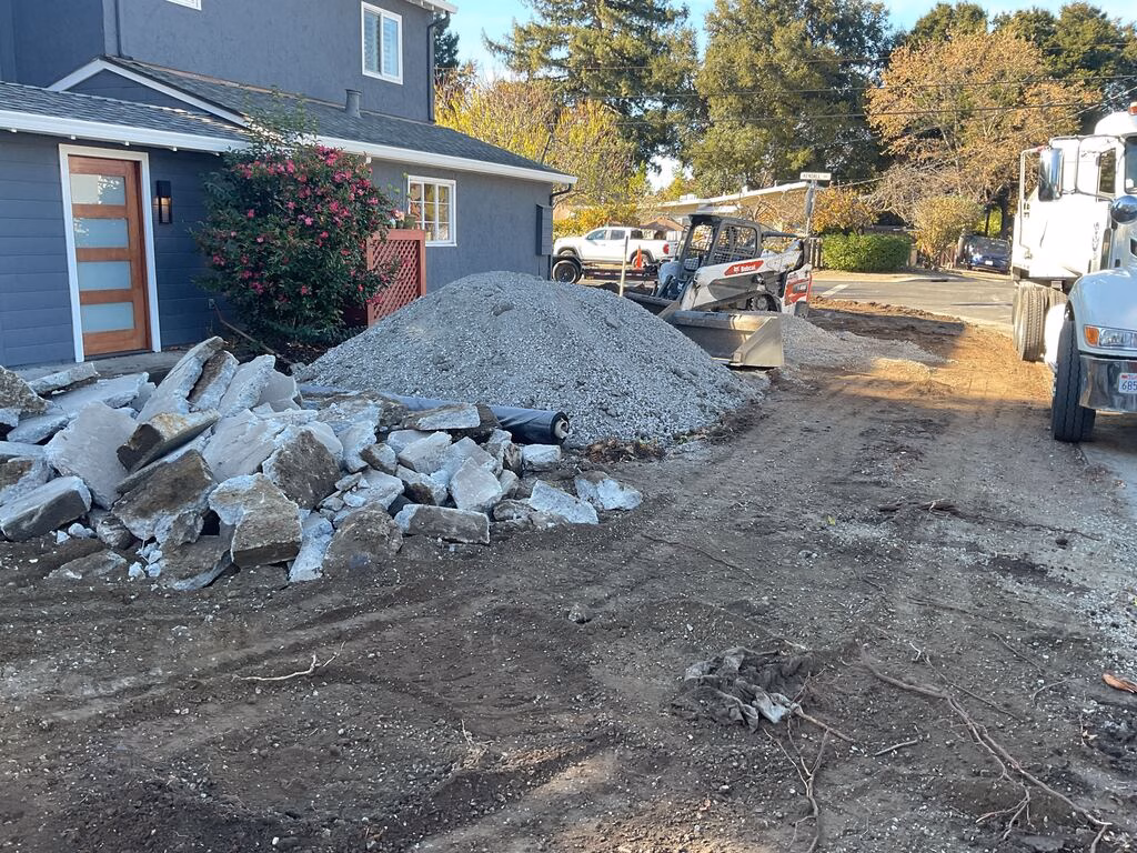 Front driveway demolition and site prep at a residential property. Large pile of broken concrete and a separate...