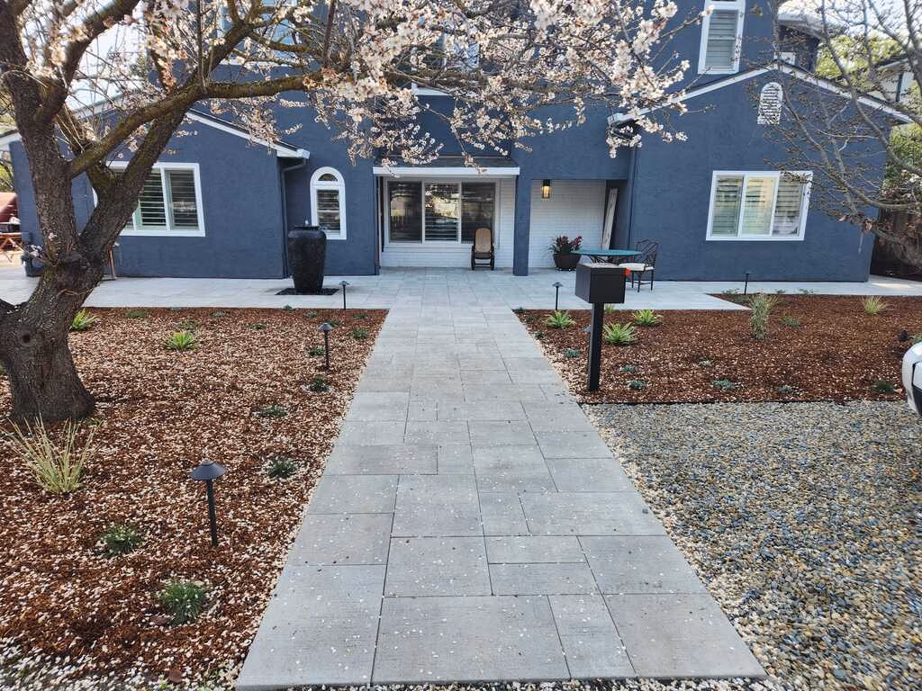 Finished interlocking concrete paver walkway and adjoining paver patio leading to the front entry of a residential home....