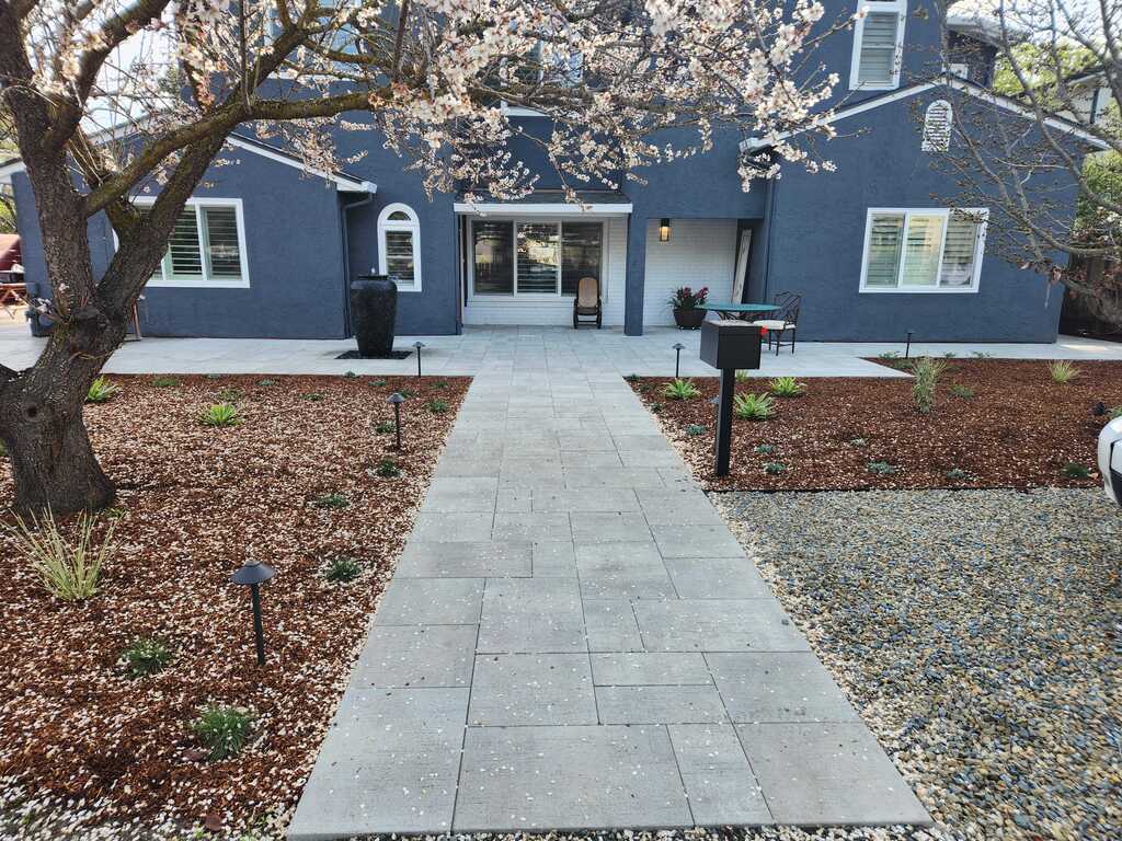 Finished interlocking concrete paver walkway and adjoining paver patio leading to the front entry of a residential home....