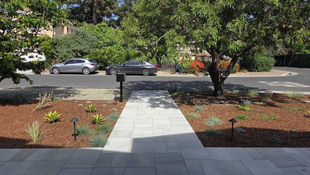 Completed front-yard installation showing a straight paver walkway of large-format rectangular pavers tying into the...