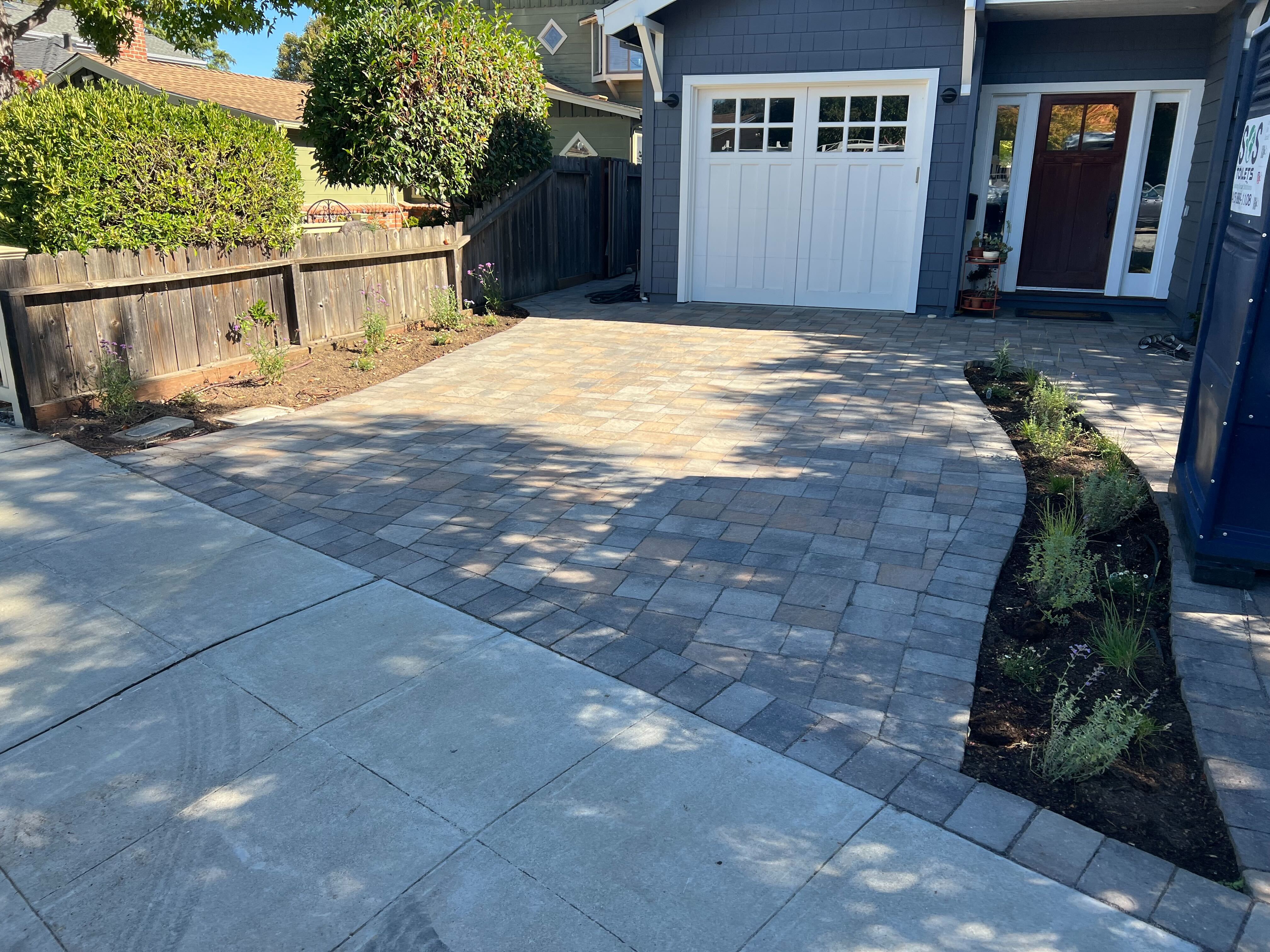 Finished interlocking paver driveway and entry walkway with a contrasting border course and a curved planting bed...