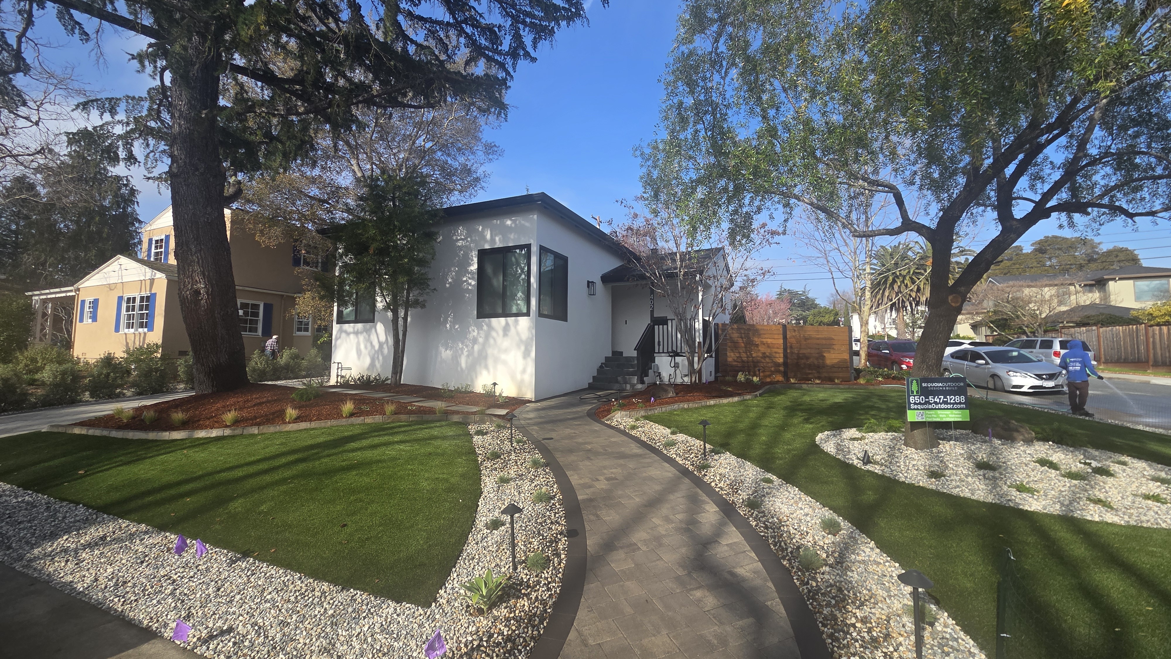 Finished curved walkway view with turf, river rock, path lighting, and clean entry circulation.