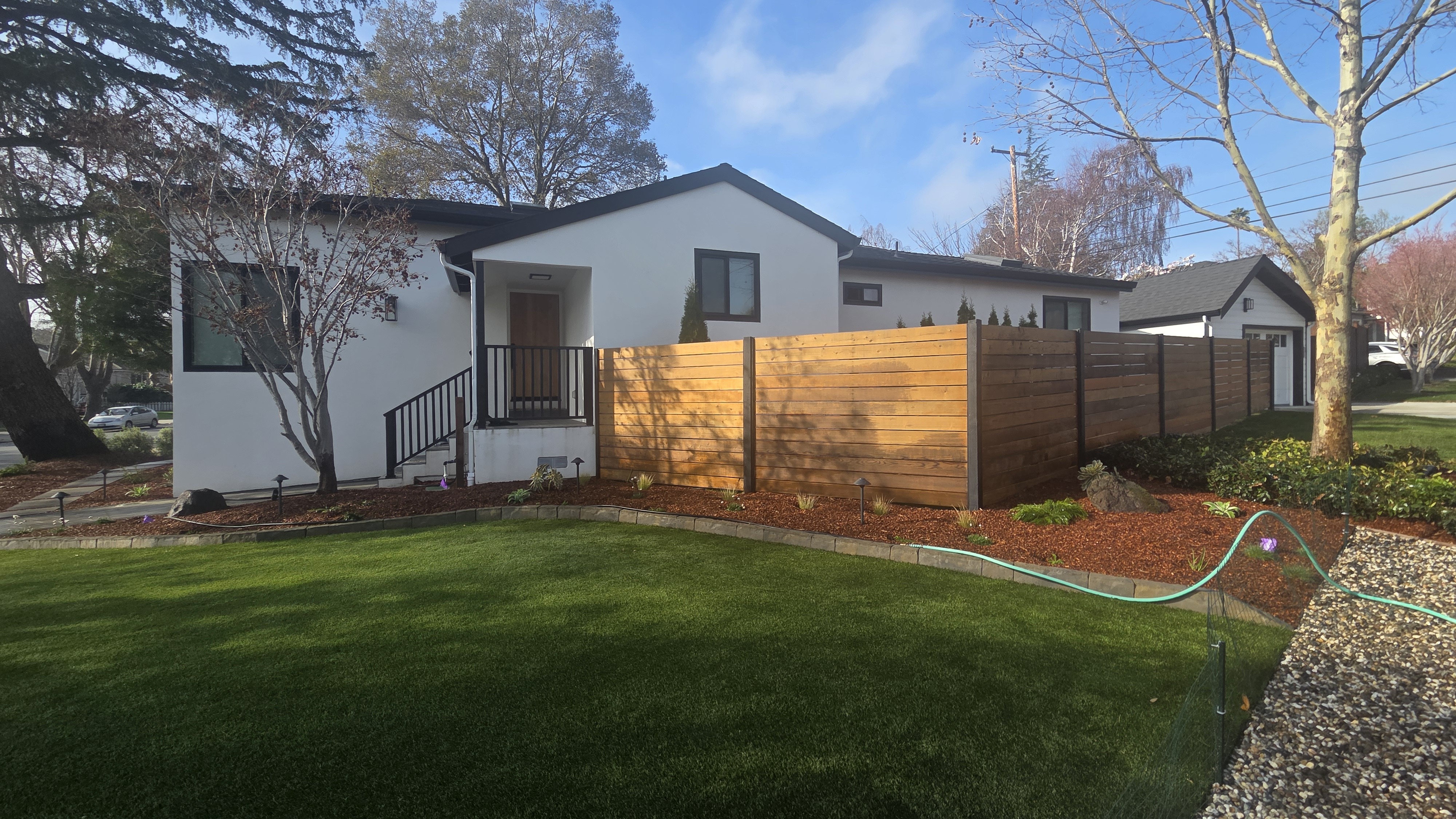 Finished side-yard turf and privacy-fence view with clean planting edges.