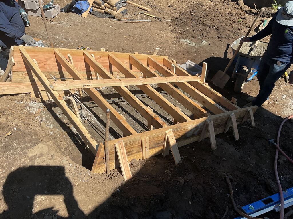 Wood formwork and steel rebar set for the concrete stair footing before the pour.