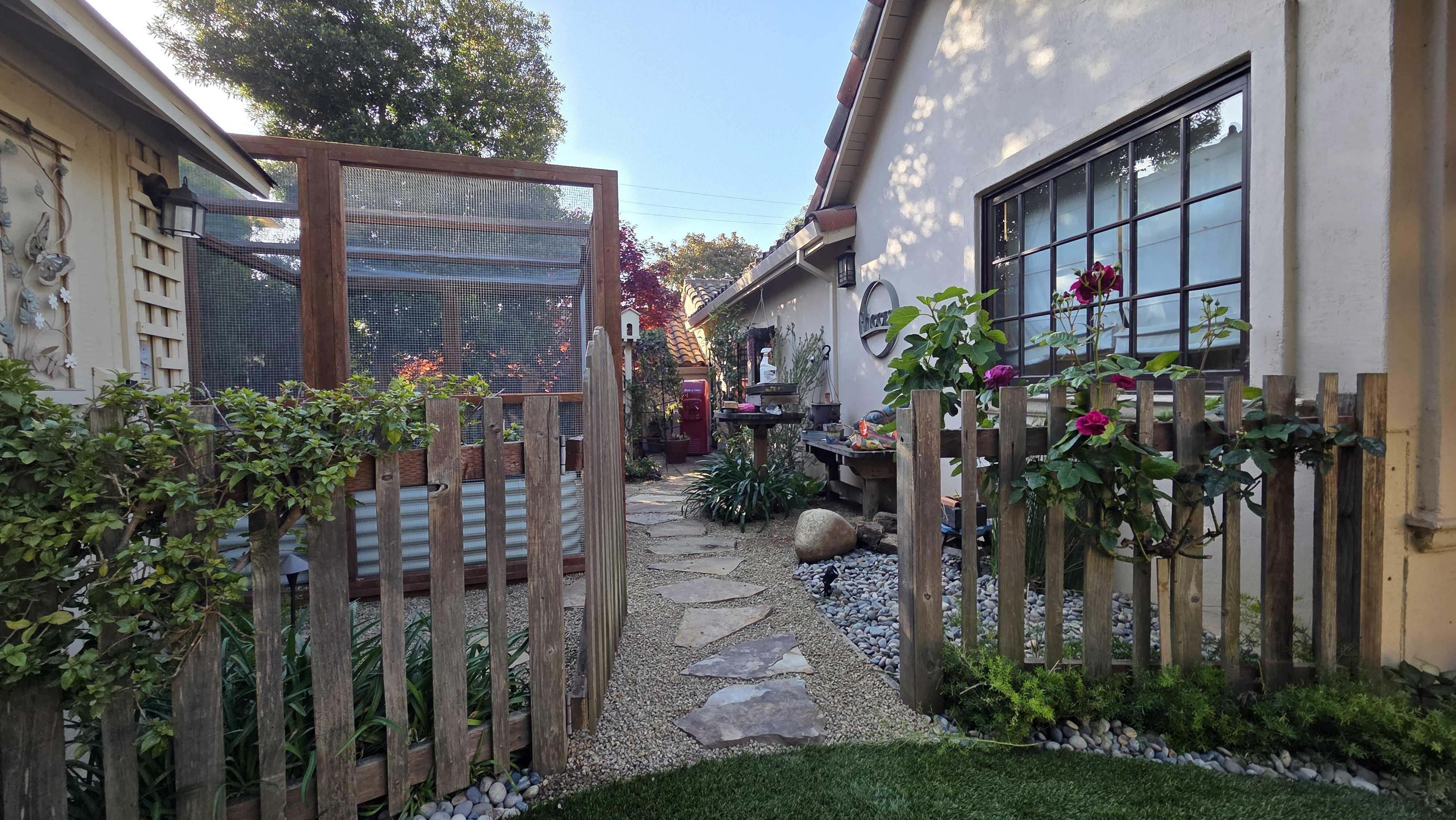 Flagstone path and decomposed-granite side garden beside the cedar-framed enclosure.