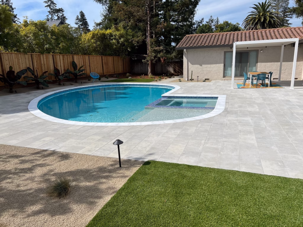 Kidney pool with white coping, paver deck, turf lawn and pool house in Los Altos, CA