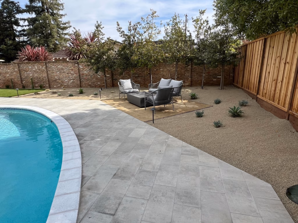 Paver pool deck meeting pea gravel planting along the reclaimed brick wall in Los Altos, CA