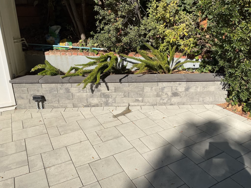 After — gray Belgard Melville wall with a dark cap at the same raised planter, new pavers at its base