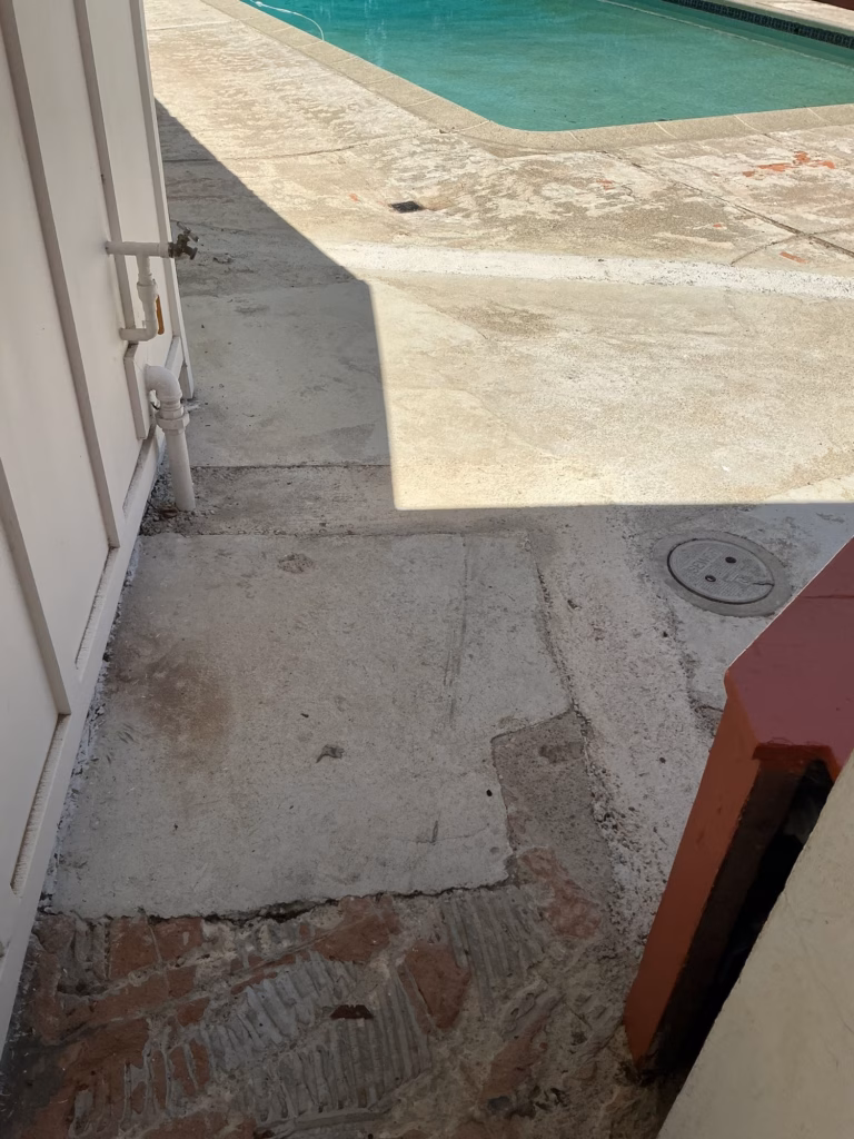 Before — patched concrete in the side passage, looking toward the pool