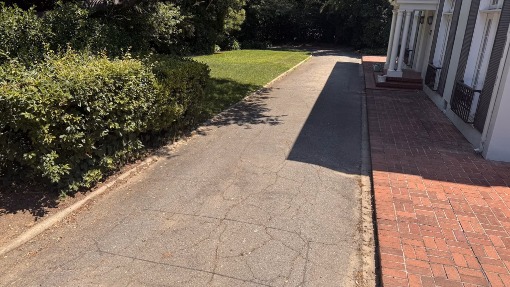 Before — cracked driveway beside a brick walkway and hedge